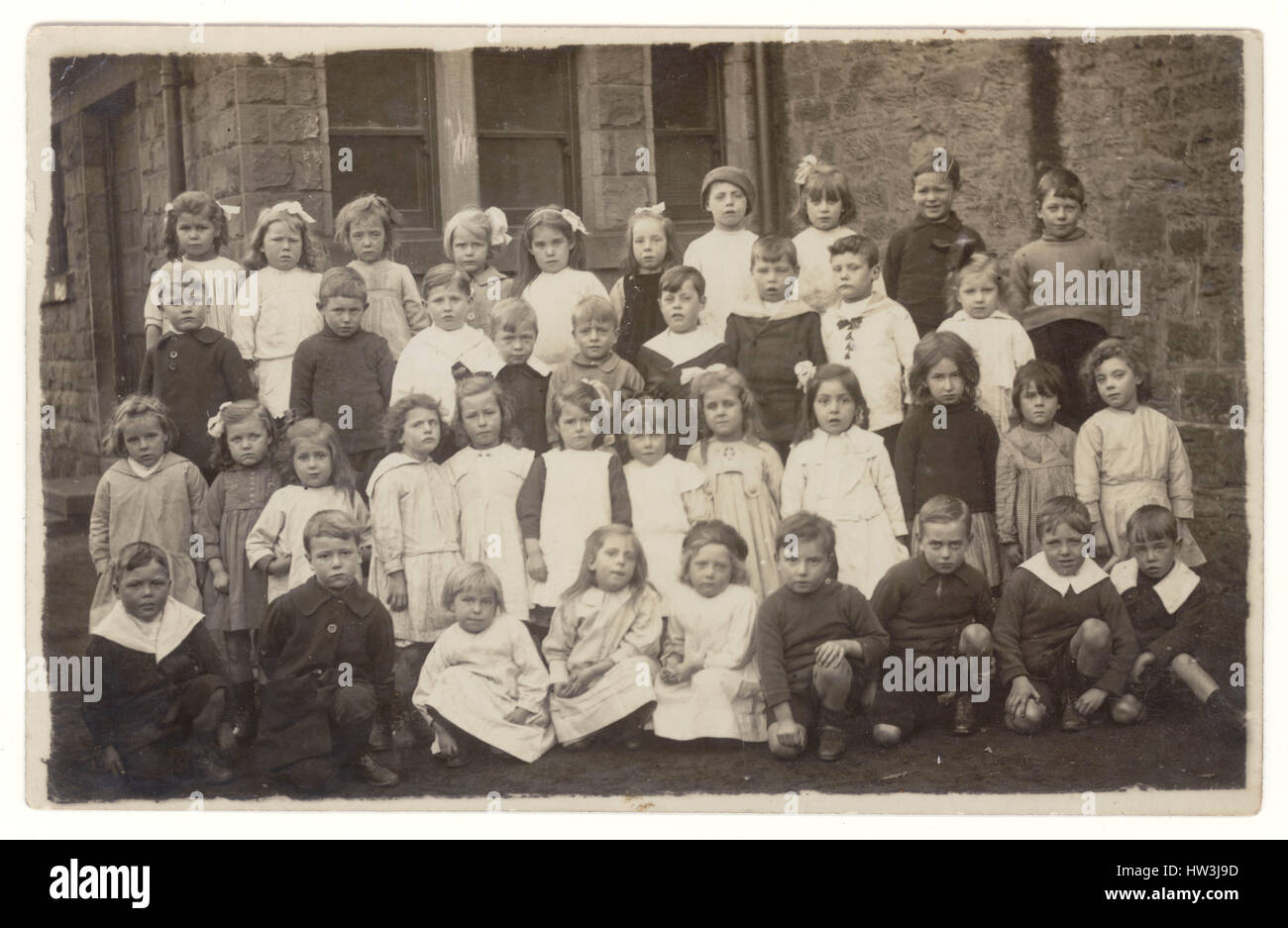 Cartolina dell'epoca edoardiana di neonati, bambini edoardiani, al di fuori di una scuola elementare, circa 1910, Regno Unito Foto Stock