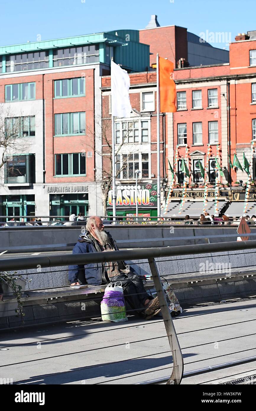 Senzatetto uomo seduto su Rosie Hackett ponte in Dublino Irlanda, senzatetto concetto, senzatetto concetto, quays irish giornata di sole Foto Stock