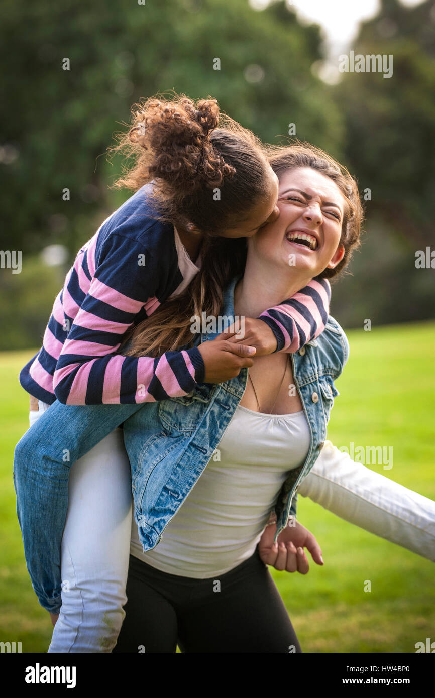 Ritratto di ragazza ridere portando la sorella piggyback Foto Stock