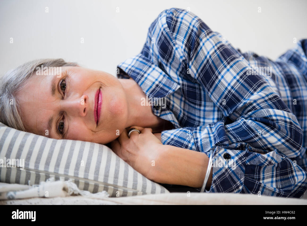 Sorridente donna caucasica la posa sul cuscino Foto Stock