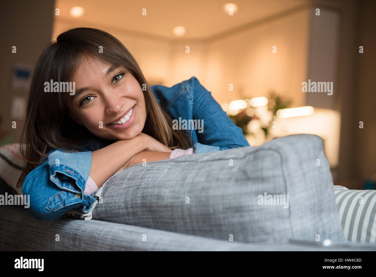 Sorridente razza mista donna appoggiata sul divano Foto Stock