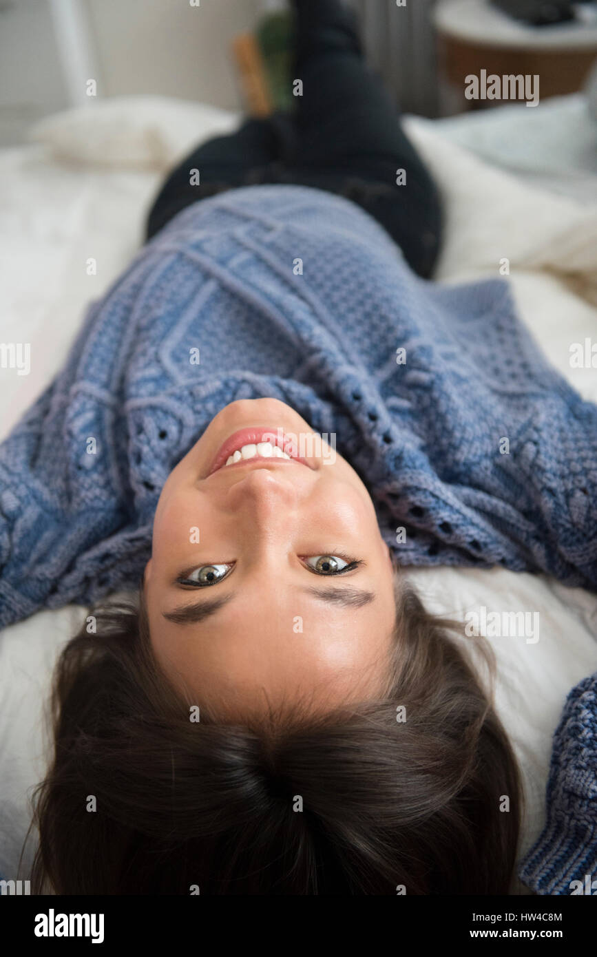 Sorridente razza mista donna posa sul letto Foto Stock