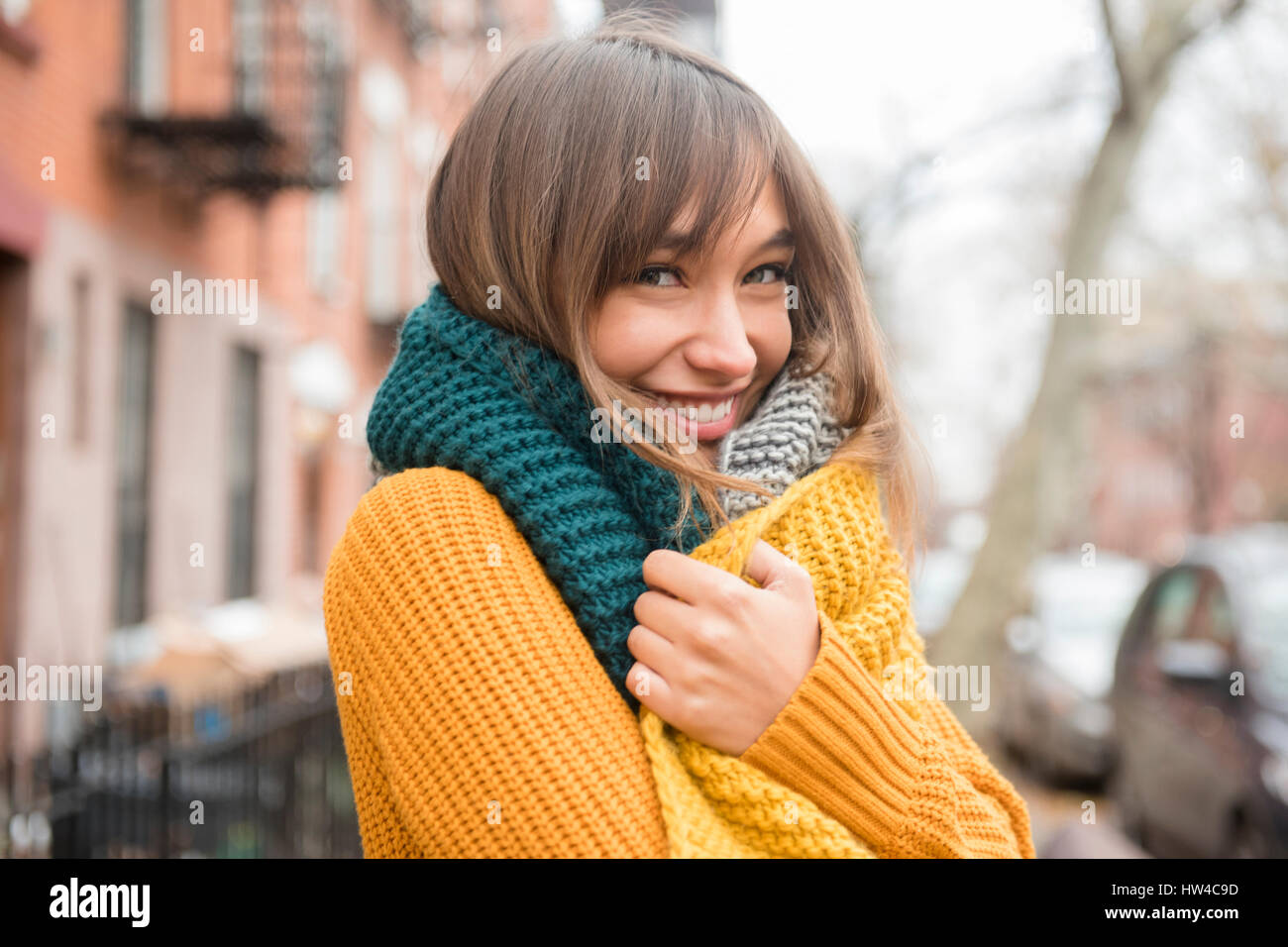 Ritratto di sorridere razza mista donna che indossa una sciarpa in città Foto Stock