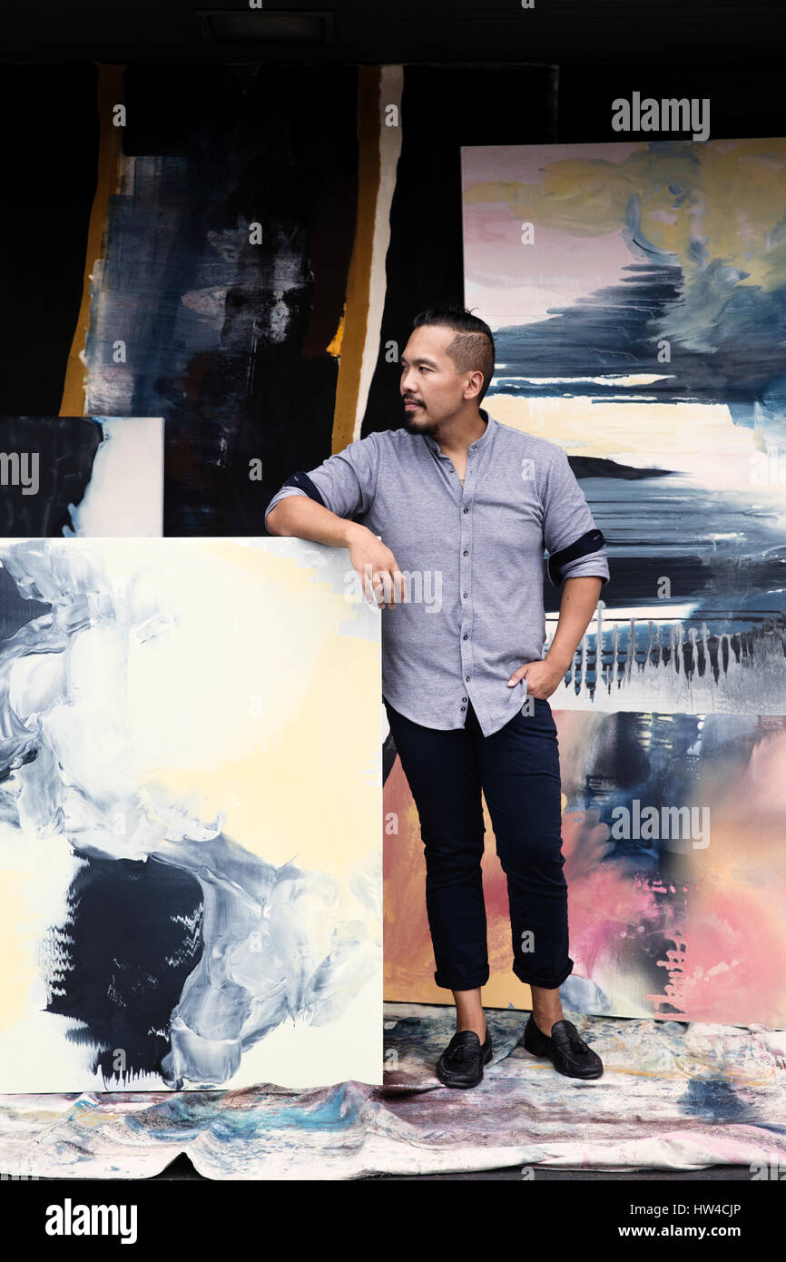 Pacific Islander artista appoggiata sui dipinti Foto Stock