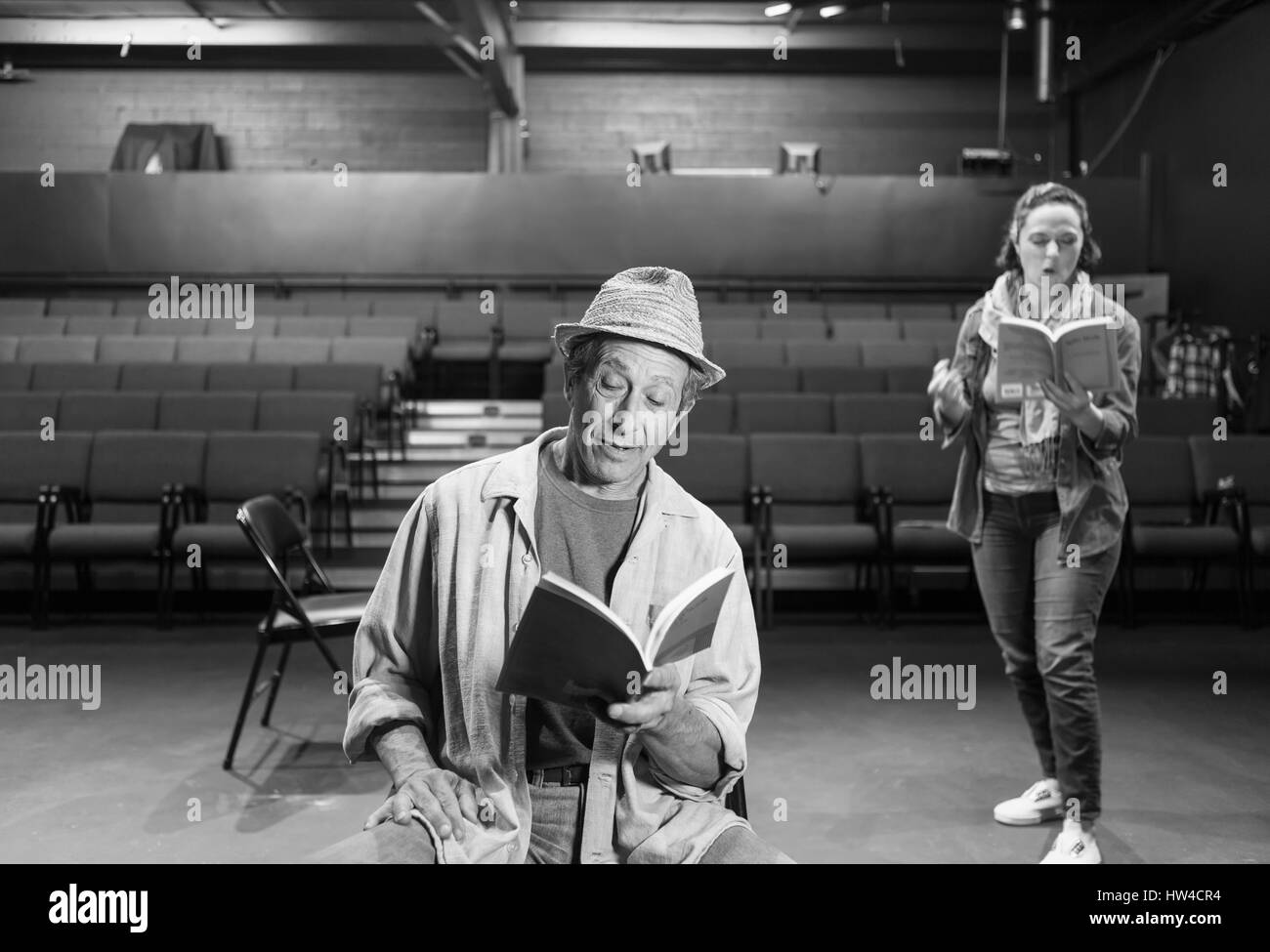 Attori caucasici ripassando con script in teatro Foto Stock