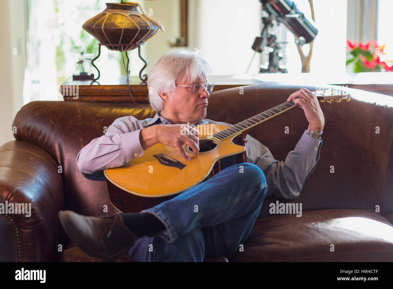 Uomo caucasico suonando la chitarra sul divano Foto Stock