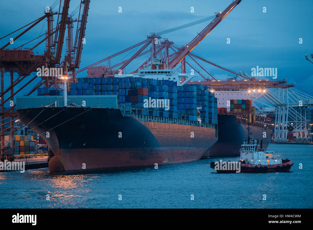 Contenitori di carico sul freighter al porto di spedizione vicino rimorchiatore Foto Stock