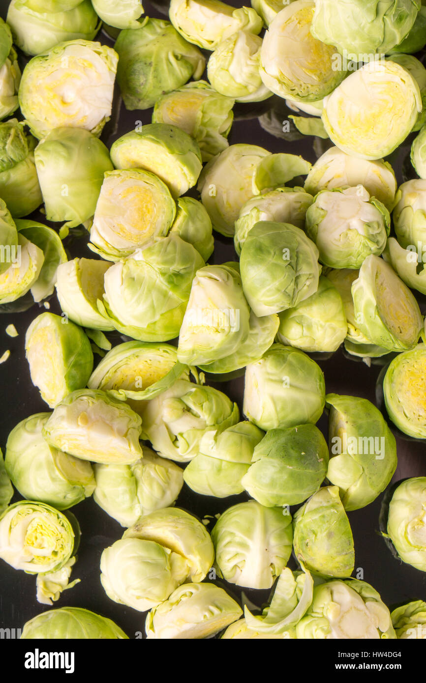 Il verde fresco intero e tagliare organici i cavoli di Bruxelles, isolato su nero sfondo lucido Foto Stock