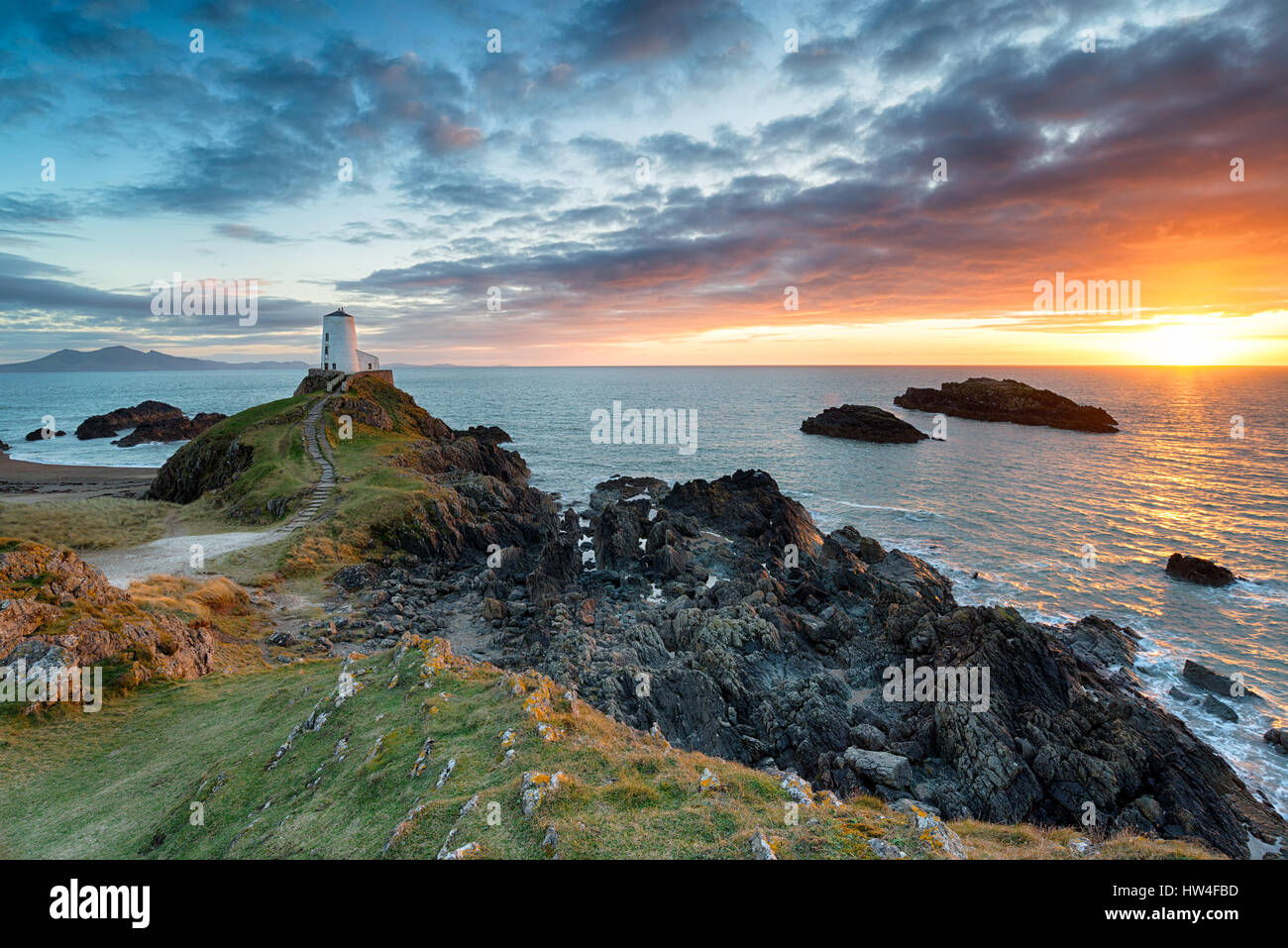 Incredibile tramonto oltre la Twr Mawr faro sulla Ynys Llanddwyn sulla costa di Anglesey nel Galles del nord Foto Stock