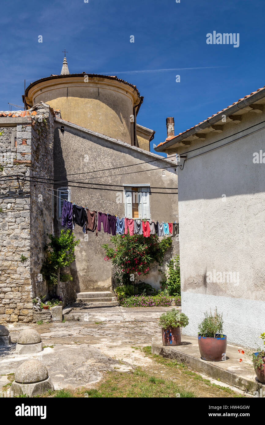 Di pietra e case in stucco, una chiesa e servizio lavanderia appeso tra due edifici in italiano medievale e la città croata di Buzet. Foto Stock