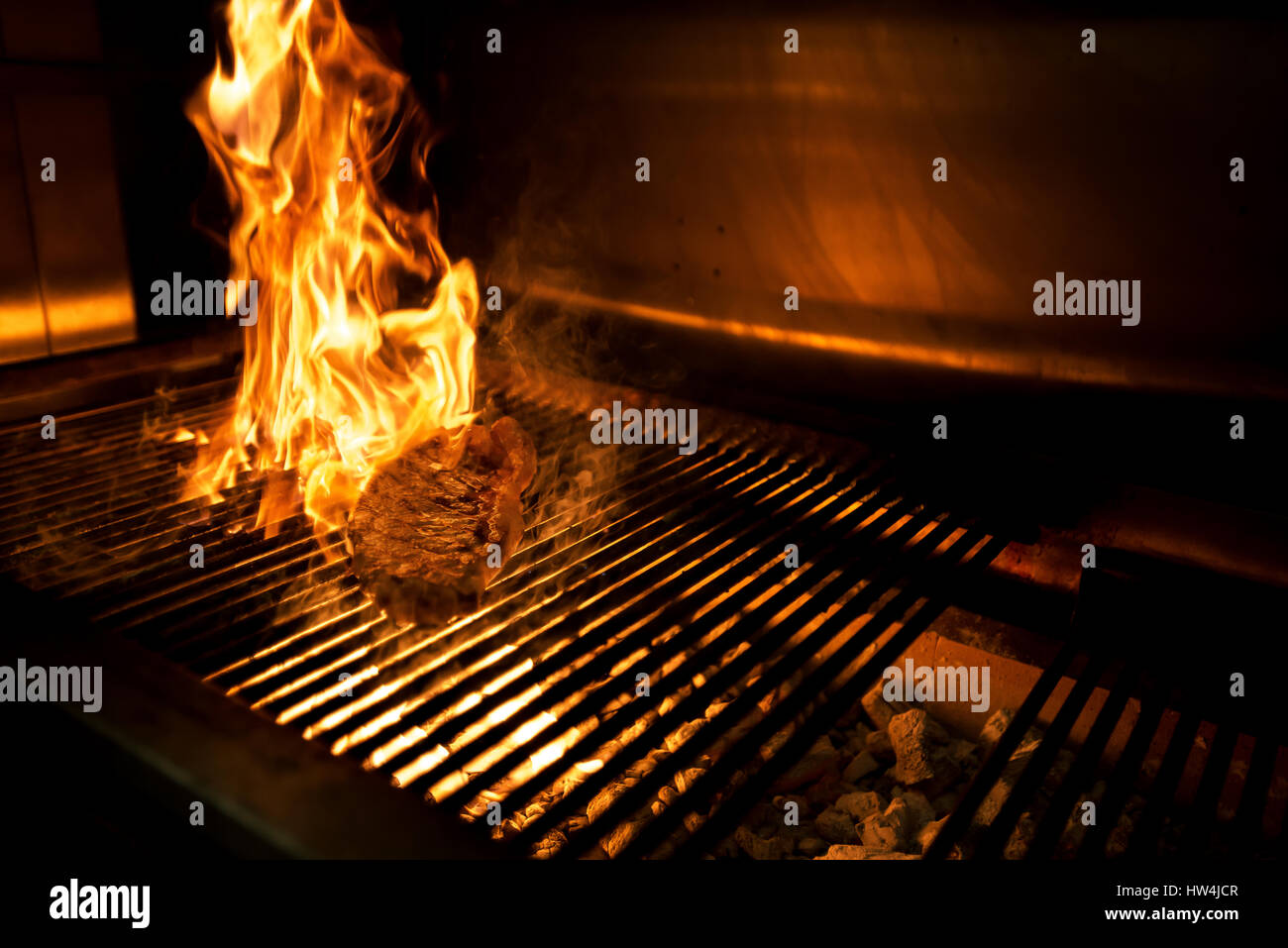 Le fiamme che lambisce una bistecca sulla griglia a carbone Foto Stock