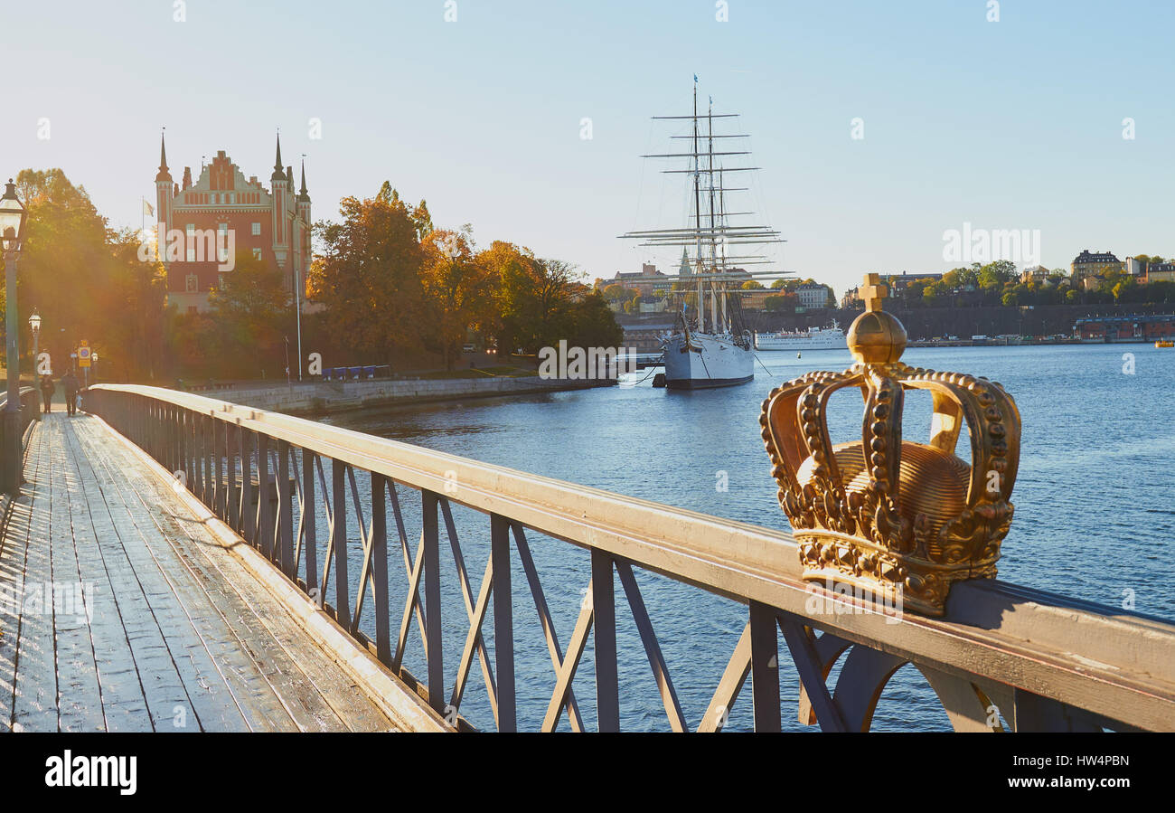 Ponte di Skeppsholmsbron in autunno la luce solare con af Chapman veliero, ora un ostello della gioventù, ormeggiato a isola di Skeppsholmen, Stoccolma, Svezia. Foto Stock