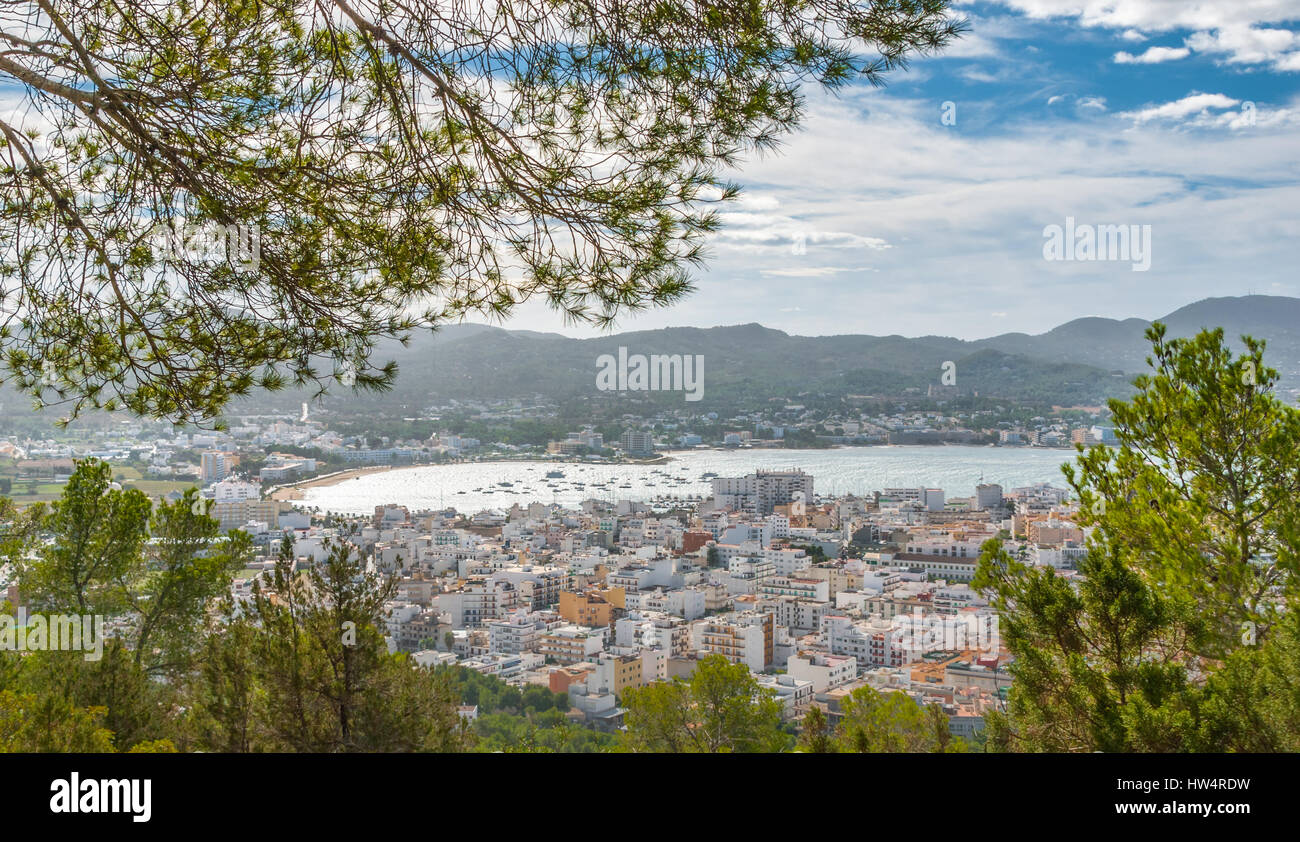 Visualizzare naturalmente attraverso gli alberi di framing, dalla collina della vicina città: San Antonio Sant Antoni de Portmany a Ibiza. Marina con barche ormeggiate. Foto Stock