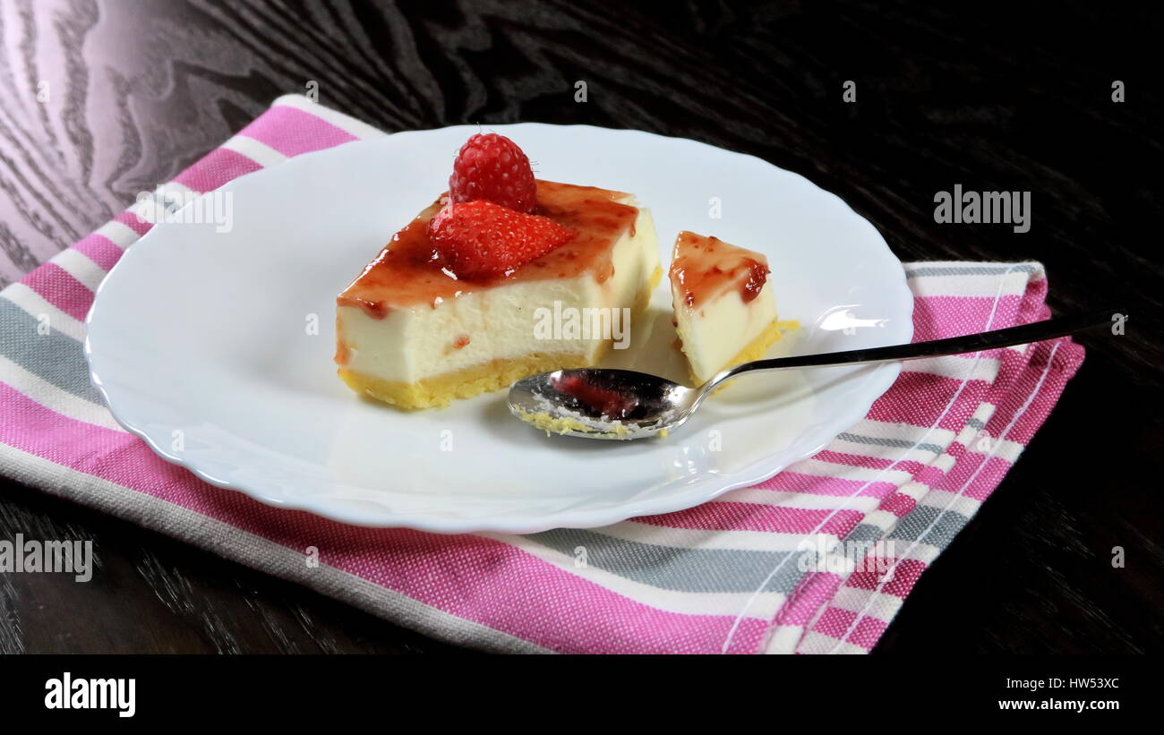 Frutti di bosco (lampone, mirtillo e fragola) mini cheesecake in un piatto bianco colorato su un panno da cucina con cucchiaino - Dessert comfort food Foto Stock