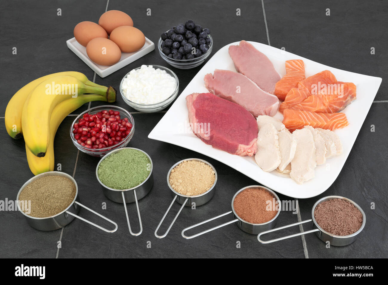 Della salute alimentare per i costruttori del corpo con carne magra, salmone, latticini, frutta e polveri supplemment su sfondo di ardesia. Foto Stock
