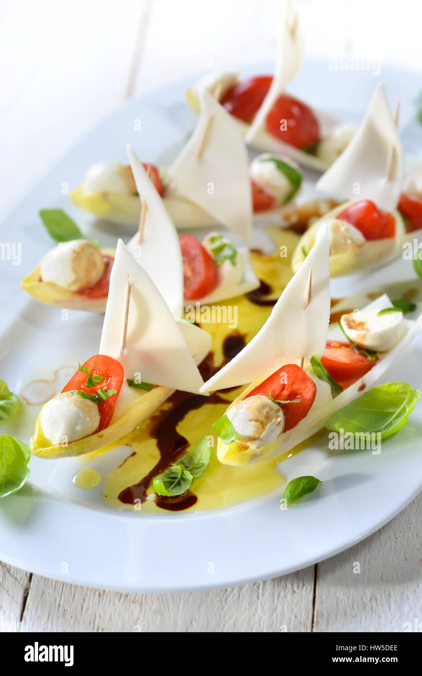 Foglie di cicoria farcita con pomodorini e mozzarella sfere, conditi con olio di oliva e aceto balsamico Foto Stock