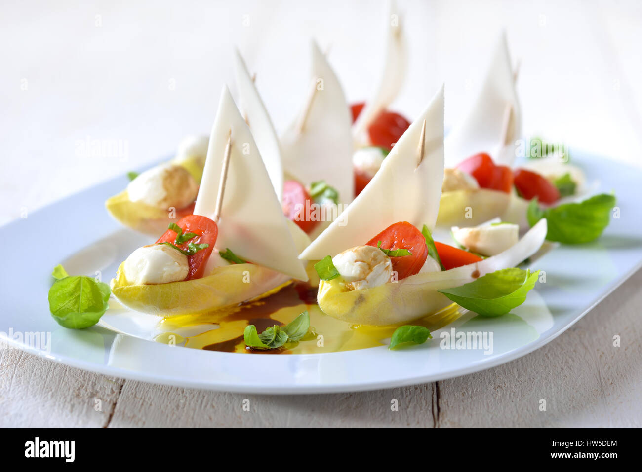 Foglie di cicoria farcita con pomodorini e mozzarella sfere, conditi con olio di oliva e aceto balsamico Foto Stock