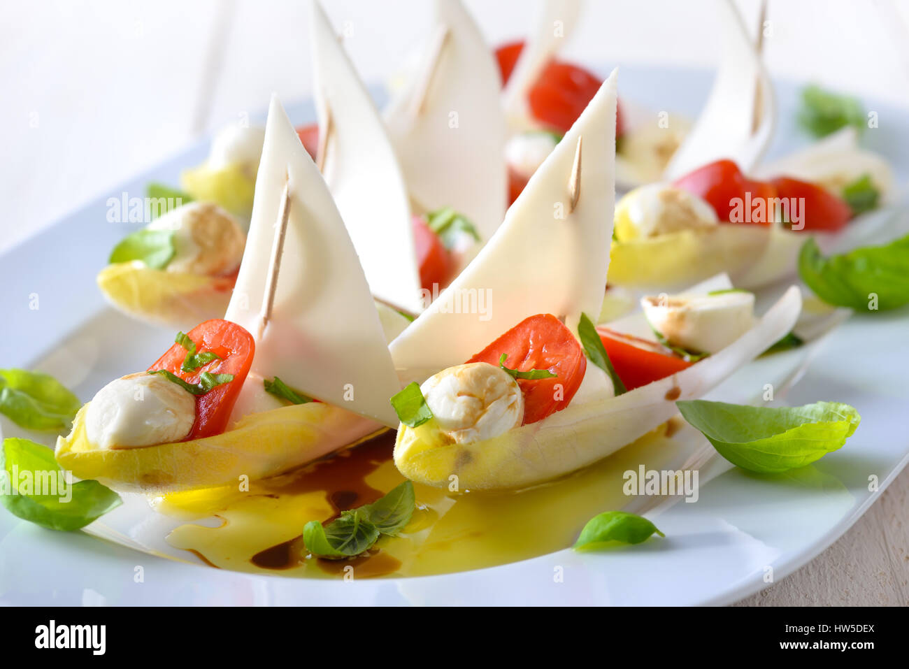 Foglie di cicoria farcita con pomodorini e mozzarella sfere, conditi con olio di oliva e aceto balsamico Foto Stock