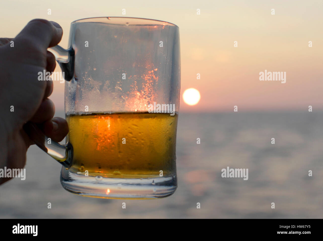 Un viaggiatore in toast il sole al tramonto con una birra a bordo di una nave nelle Galapagos. Foto Stock