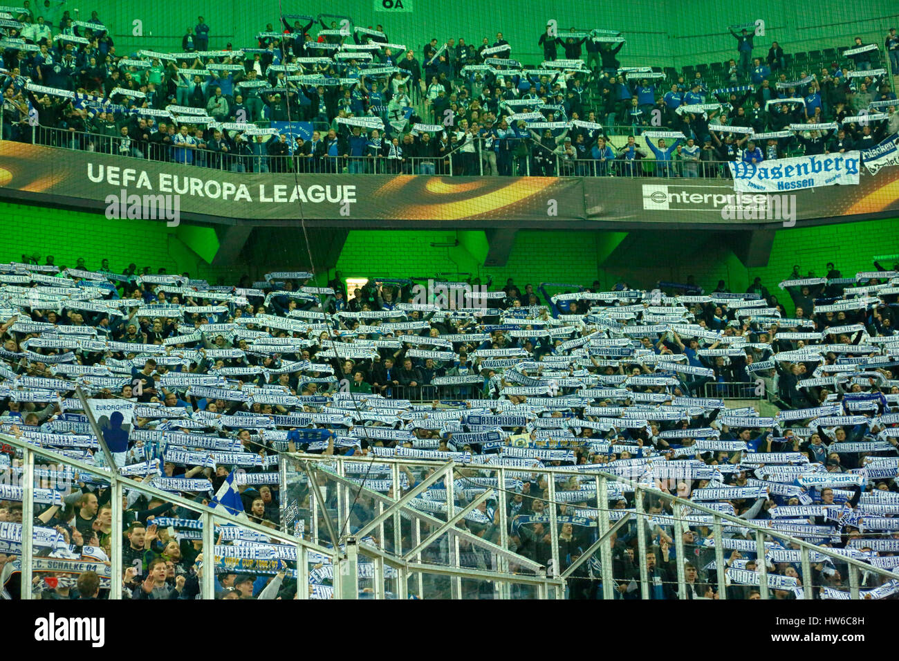 Sport calcio UEFA Europa League, 2016/2017, Round di 16, ritorno, Borussia Moenchengladbach vs FC Schalke 04 2:2, Stadio Borussia Park, Stadio vista, stand, sorge, visitatori spettatori appassionati di calcio di Schalke tenere sciarpe con l'etichetta Eurofighter Coppa UEFA vincitore 1997 Foto Stock