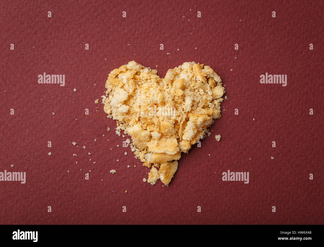 Cuore di pezzi con cracker su uno sfondo di colore rosso. Immagine del giorno di San Valentino Foto Stock