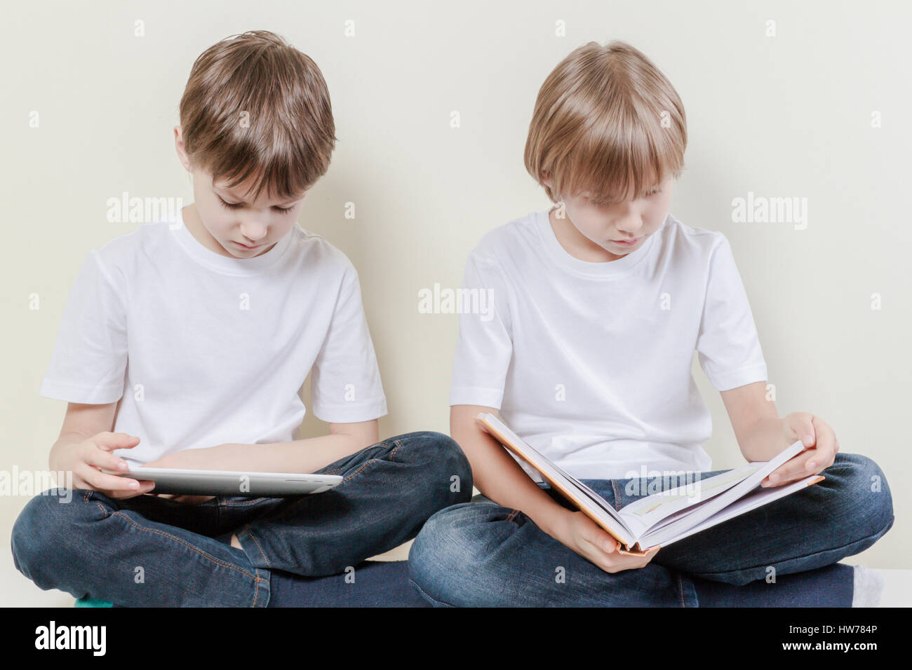 Ragazzo con computer tablet e kid leggendo un libro. Bambini Educazione nozione di piacere. Foto Stock