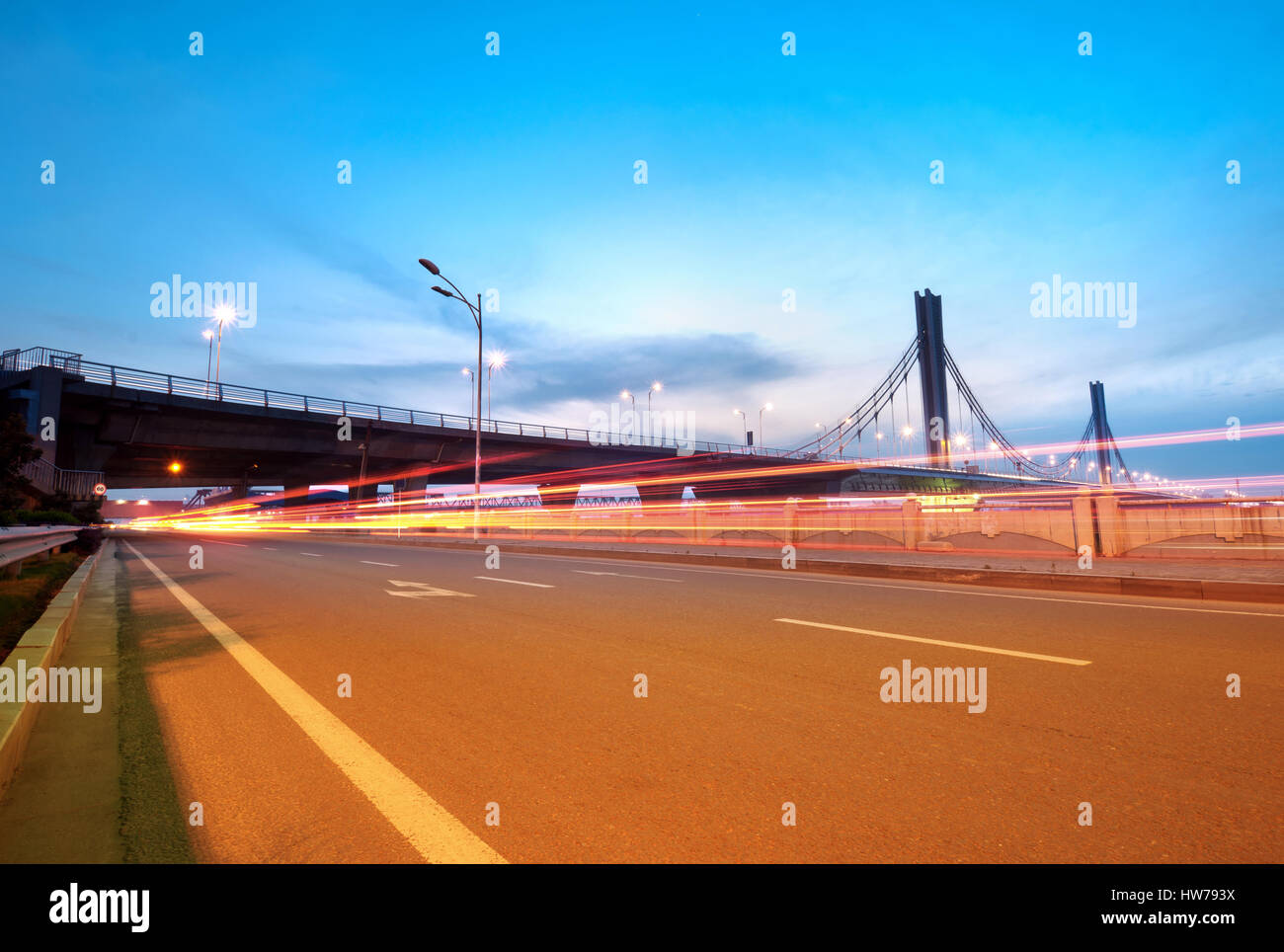 Auto sentieri di luce sul moderno ponte al tramonto Foto Stock