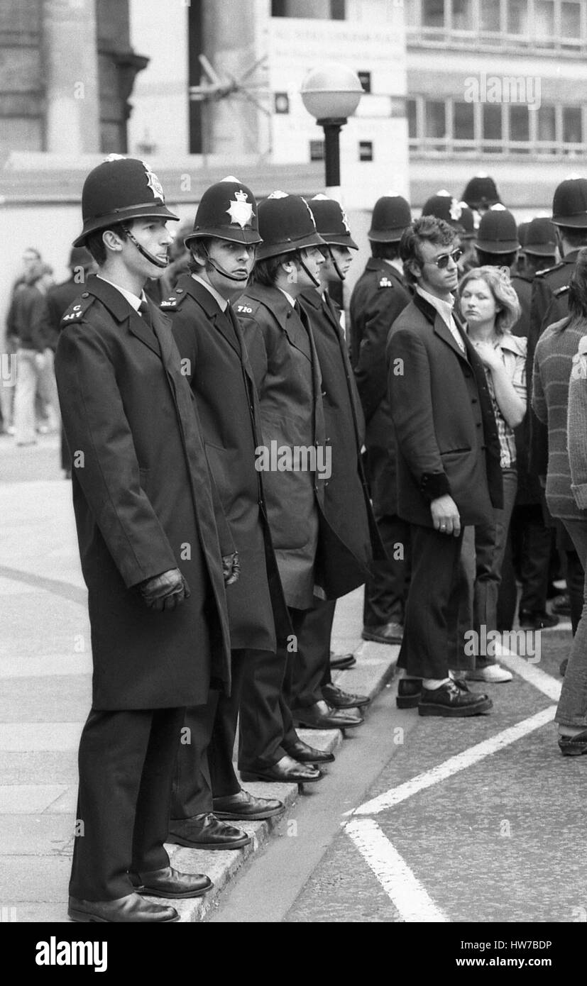 Un ventilatore di musica in Teddy Boy fashion stand con una linea di funzionari di polizia durante il Rock and Roll campagna Radio marzo nel centro di Londra, in Inghilterra il 15 maggio 1976. La campagna mira a ottenere più stile anni cinquanta il rock and roll suonato musica su BBC Radio. Foto Stock