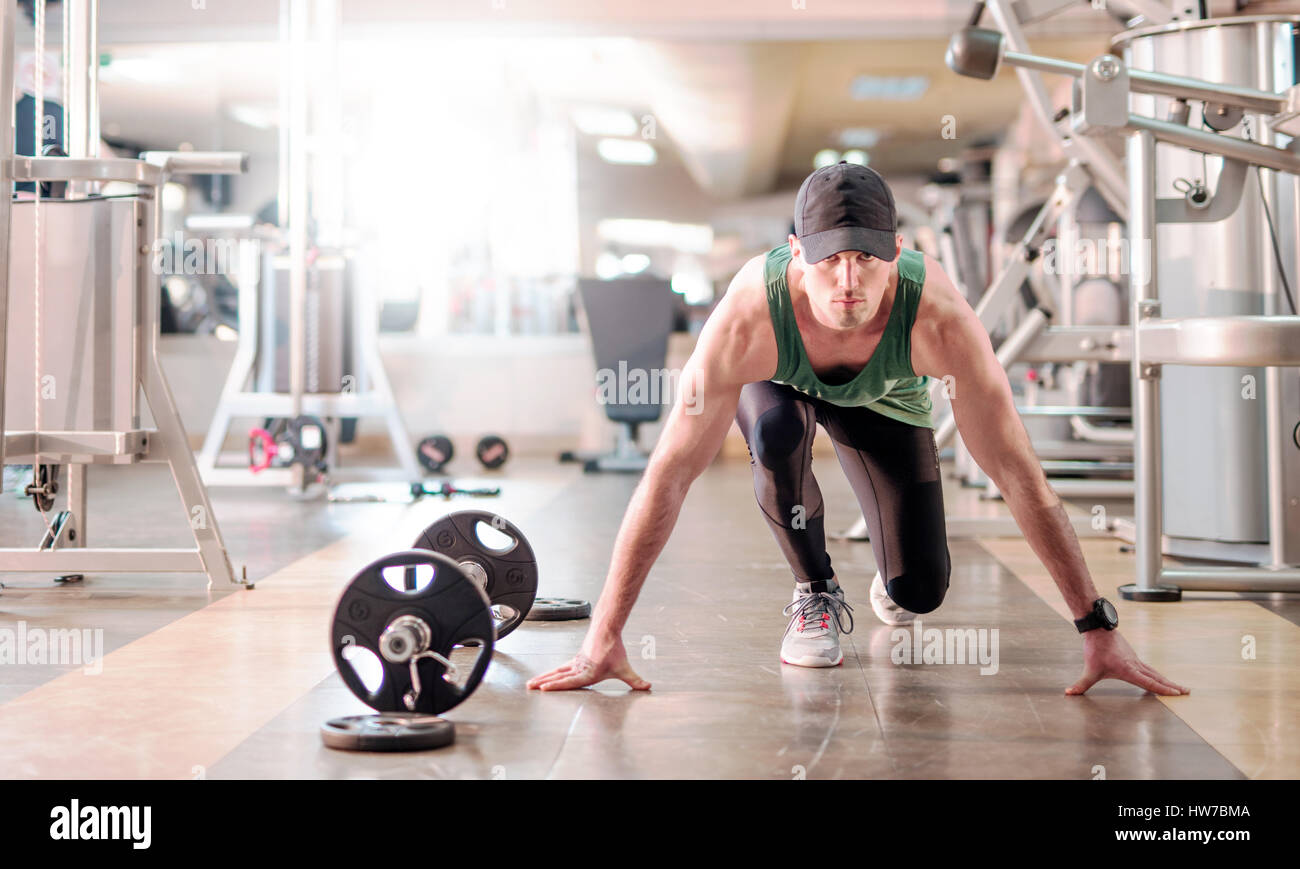 Giovani determinato athletic uomo nella posizione di avvio nel club salute Foto Stock