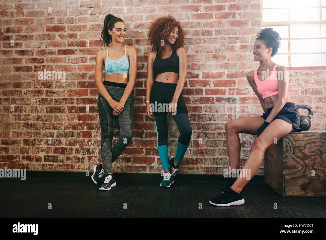 Tre razza mista donne riposo dopo un allenamento in palestra. Il relax dopo esercizio di un club salute. Foto Stock