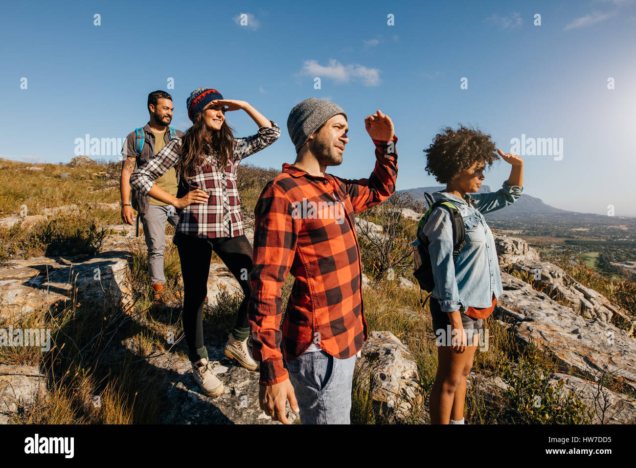Gruppo di escursionismo amici godendo la vista dal picco di montagna. Giovani uomini e donne in piedi sul picco e guardando a una vista. Foto Stock