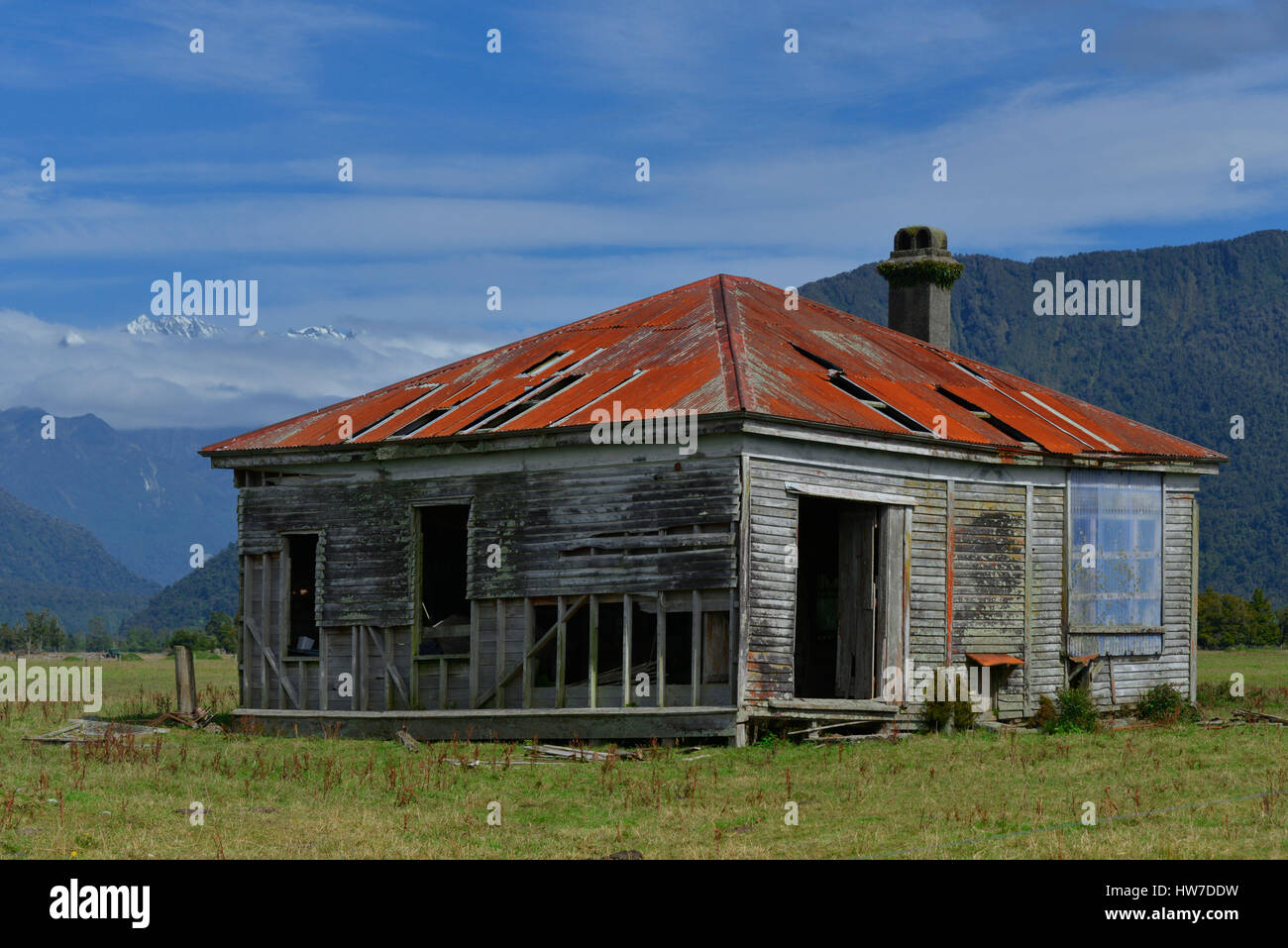 Abbandonata dal tetto di stagno house nell'Isola del Sud della Nuova Zelanda, con le Alpi del Sud in background. Foto Stock