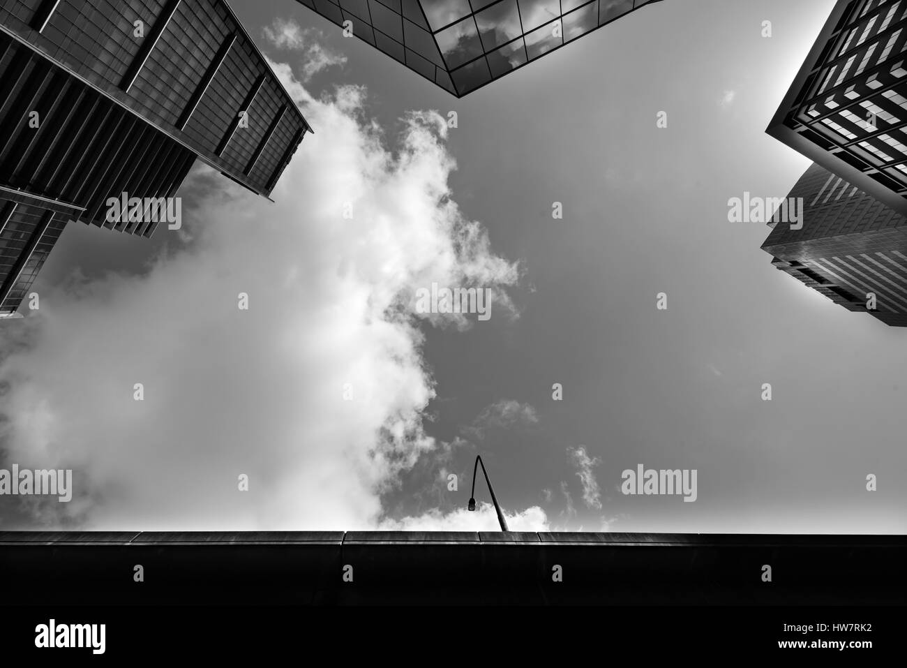 Un'immagine generica anonima monocromatica che guarda verso il cielo in uno stretto divario tra le torri in vetro che si innalzano a Sydney, Australia Foto Stock
