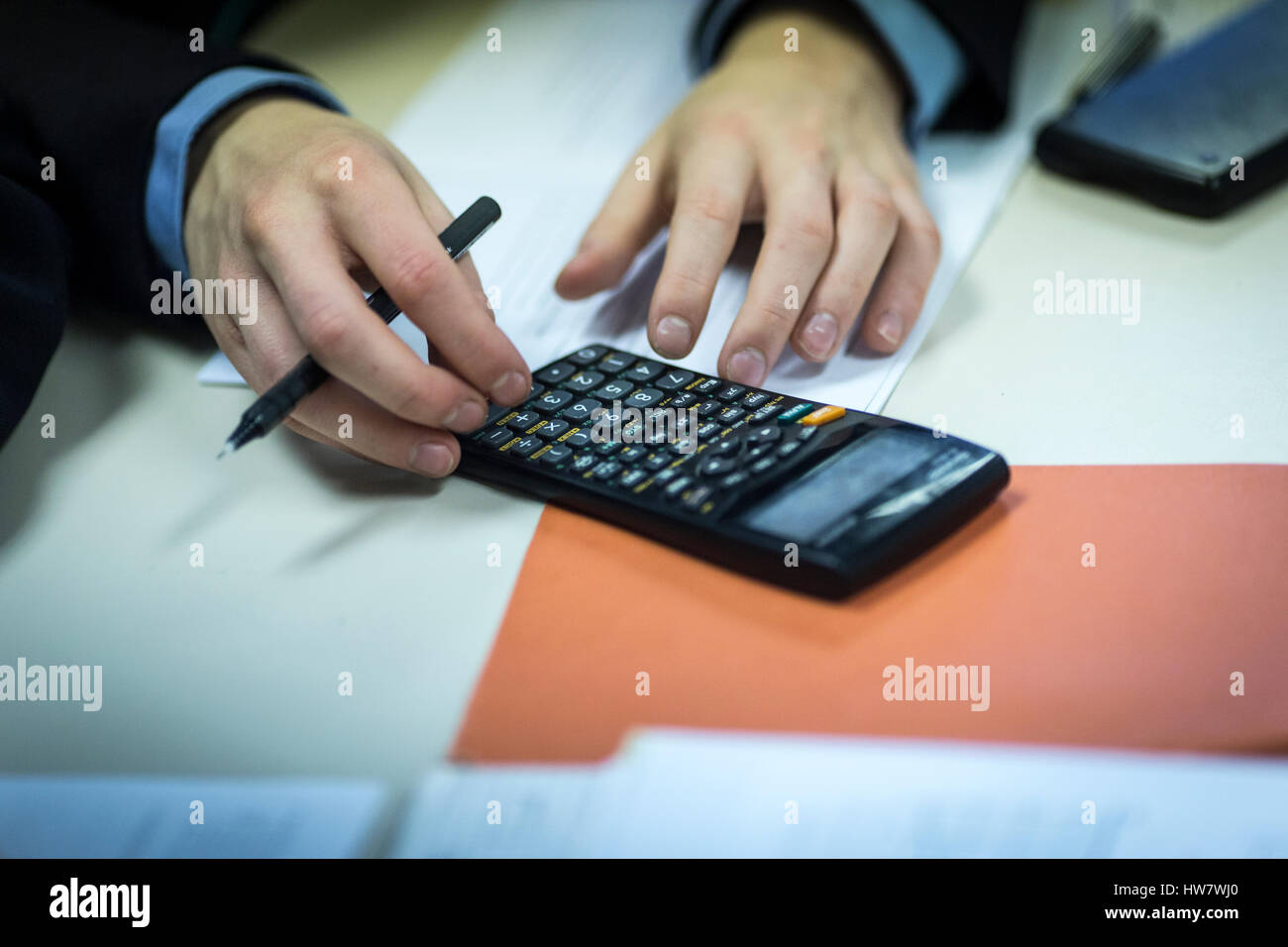 Un maschio di allievo utilizza una calcolatrice durante una lezione Foto Stock
