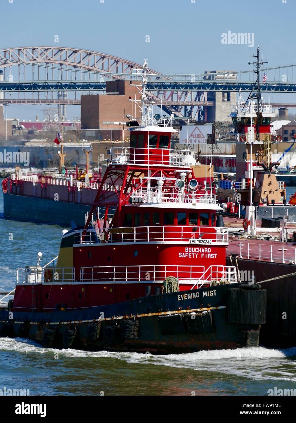 Rosso brillante rimorchiatore guide su chiatta East River. Barca commerciale del traffico. New York, New York, Stati Uniti d'America. Foto Stock