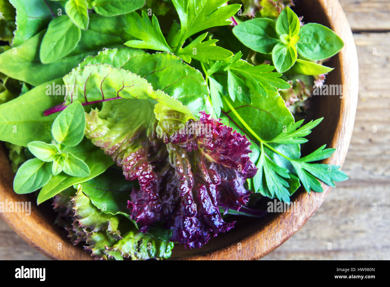 Organico fresco verde insalata mista lascia su legno rustico sfondo - Organica Vegana sana dieta vegetariana detox ingrediente alimentare Foto Stock
