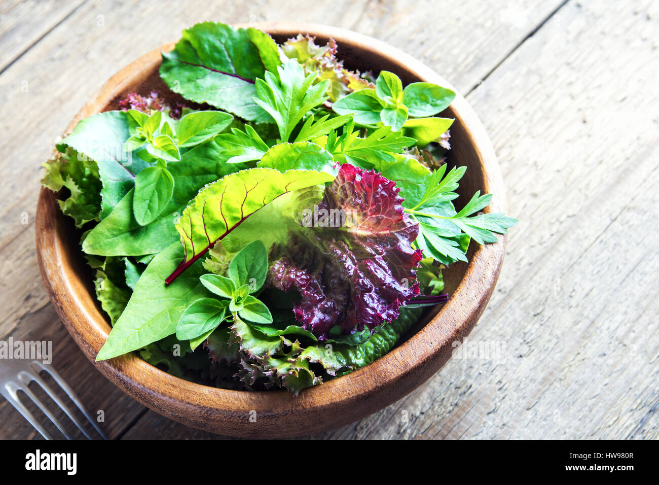 Organico fresco verde insalata mista lascia su legno rustico sfondo - Organica Vegana sana dieta vegetariana detox ingrediente alimentare Foto Stock