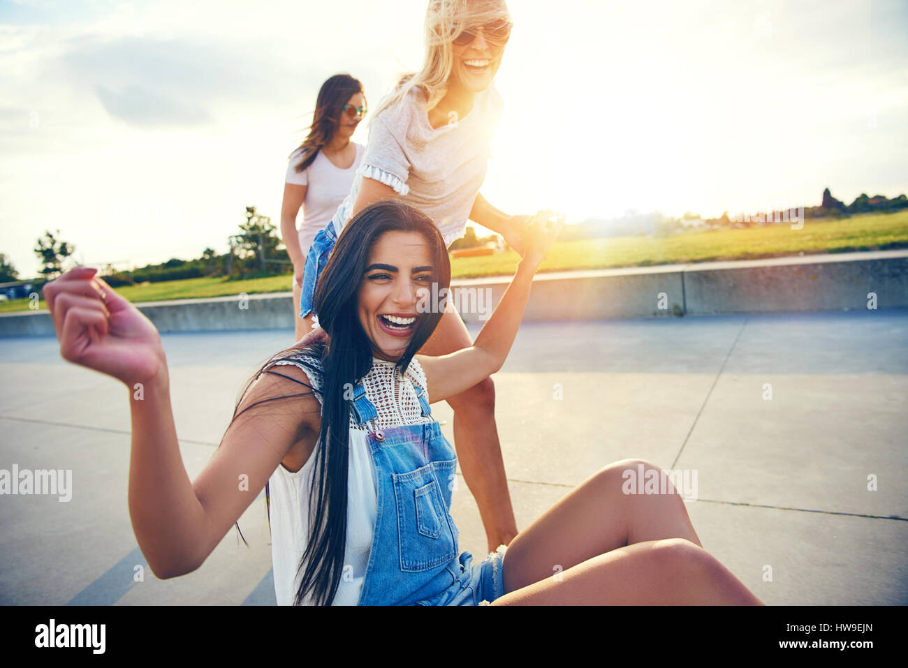 Tre giovani amici vivace in estate usura ridere mentre spendere tempo insieme contro il paesaggio soleggiato. Foto Stock