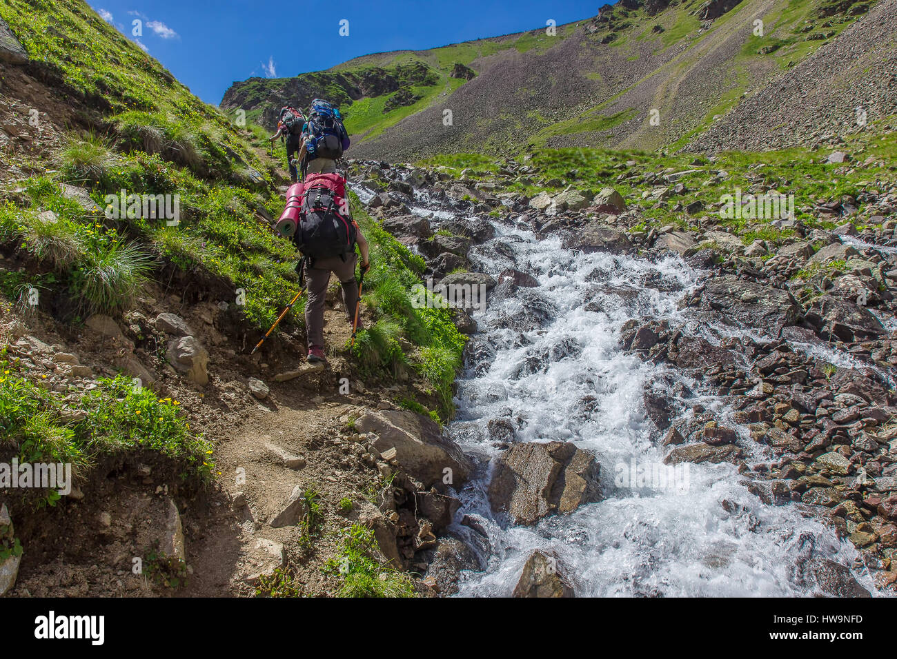 I turisti di montagna andare su per la collina lungo il fiume turbolento nelle montagne del Caucaso Foto Stock