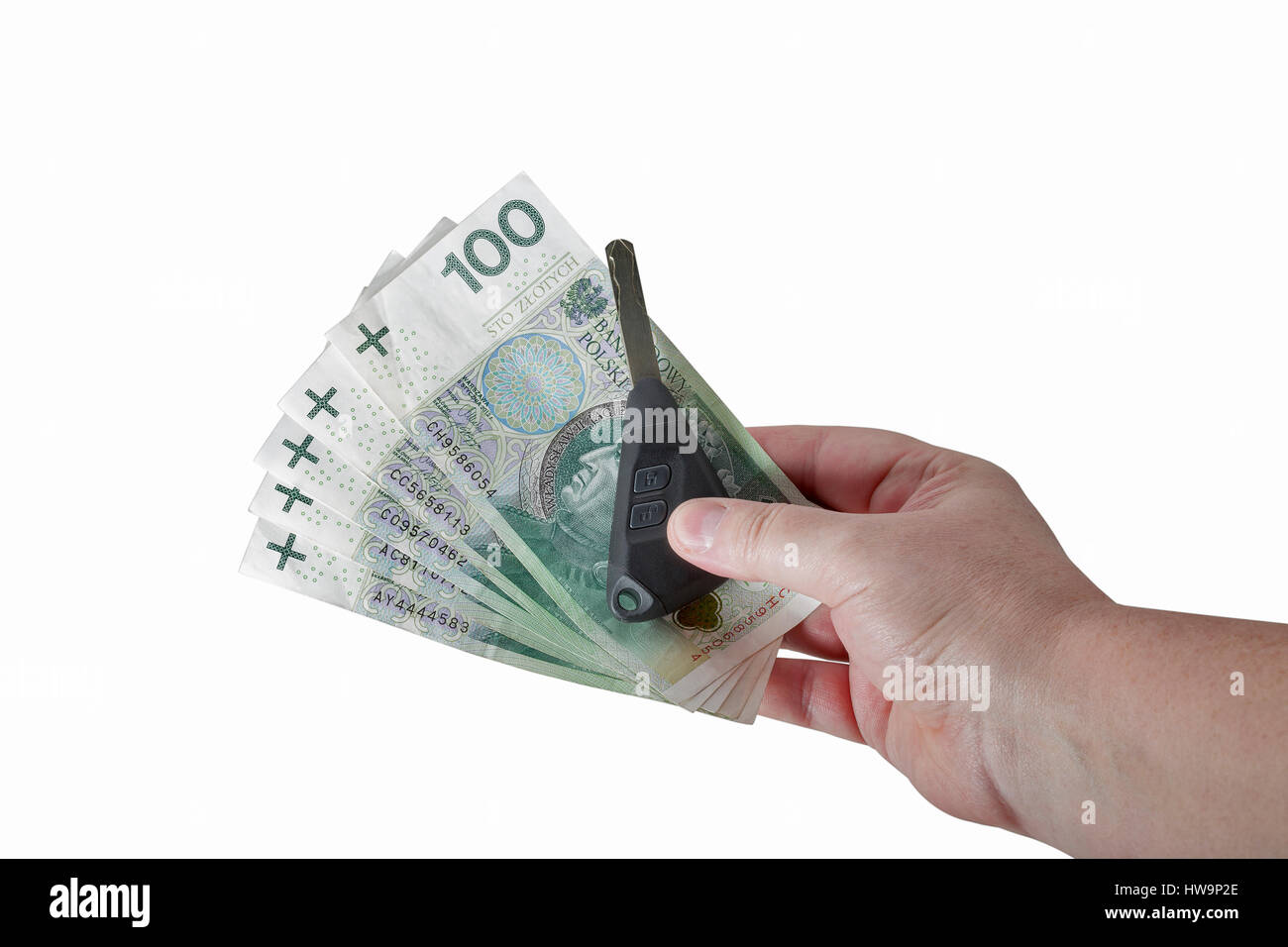 Man mano che tiene lo zloty polacco cento banconote e le chiavi dell'auto isolati su sfondo bianco closeup con spazio di copia Foto Stock
