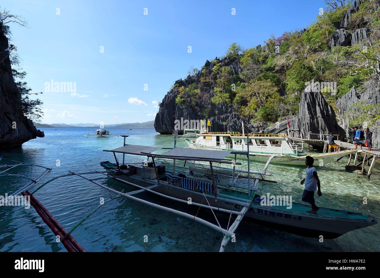 Filippine, Isole Calamian nel nord di Palawan, Coron Island Naturale Area biotiche, canoa outrigger sotto le rocce calcaree in una piccola baia Foto Stock
