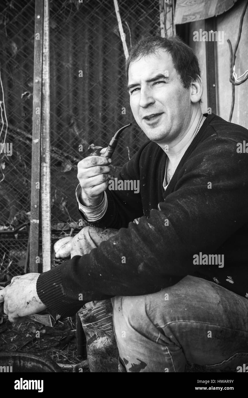 Krasnodar, Russia - 4 Marzo 2017: giovani adulti macellaio russo fumi tubo dopo un abbattimento di un toro, foto in bianco e nero Foto Stock