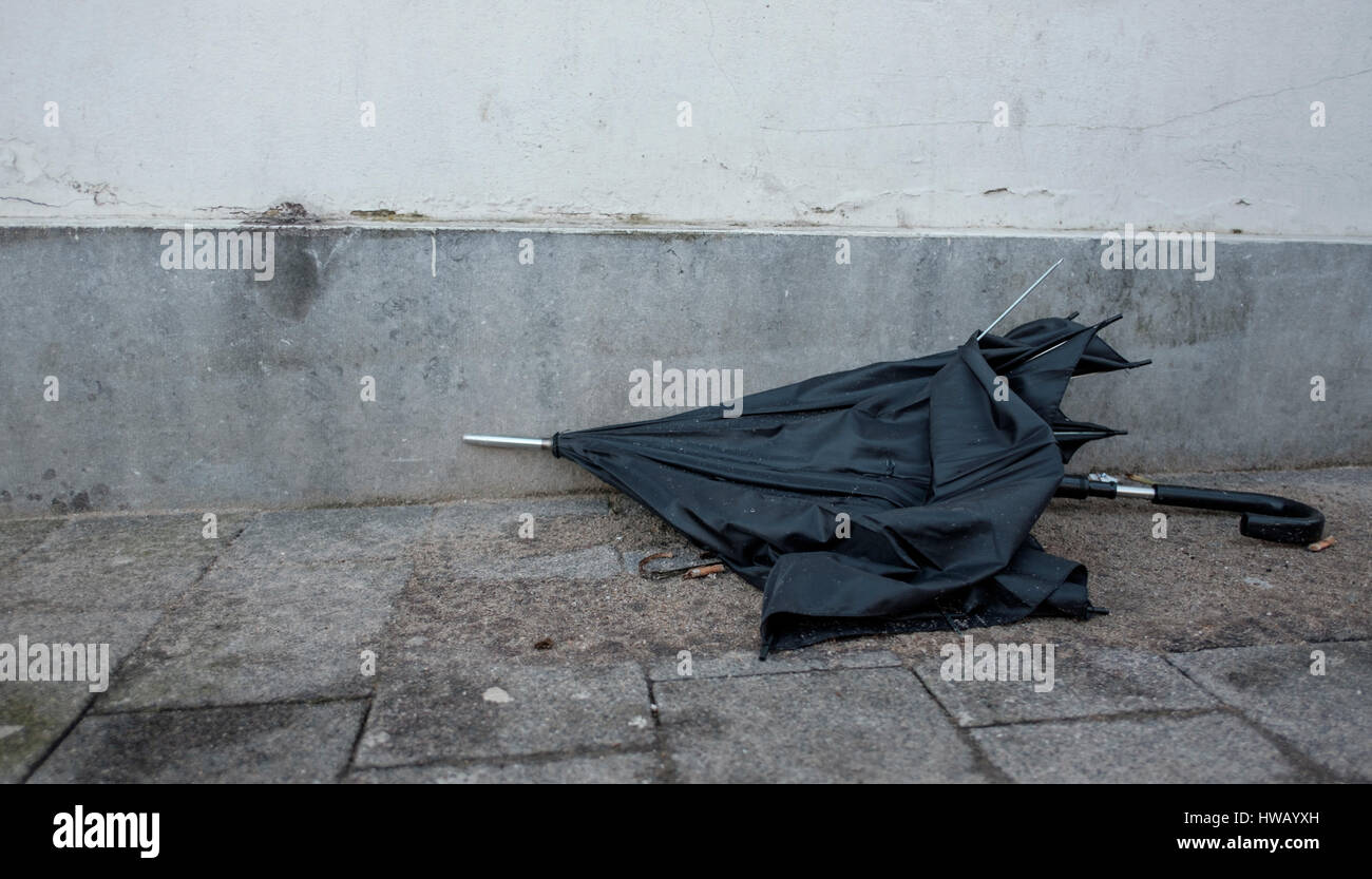 Rotto Ombrello nero è gettato via come spazzatura e giace abbandonata sulle strade Foto Stock
