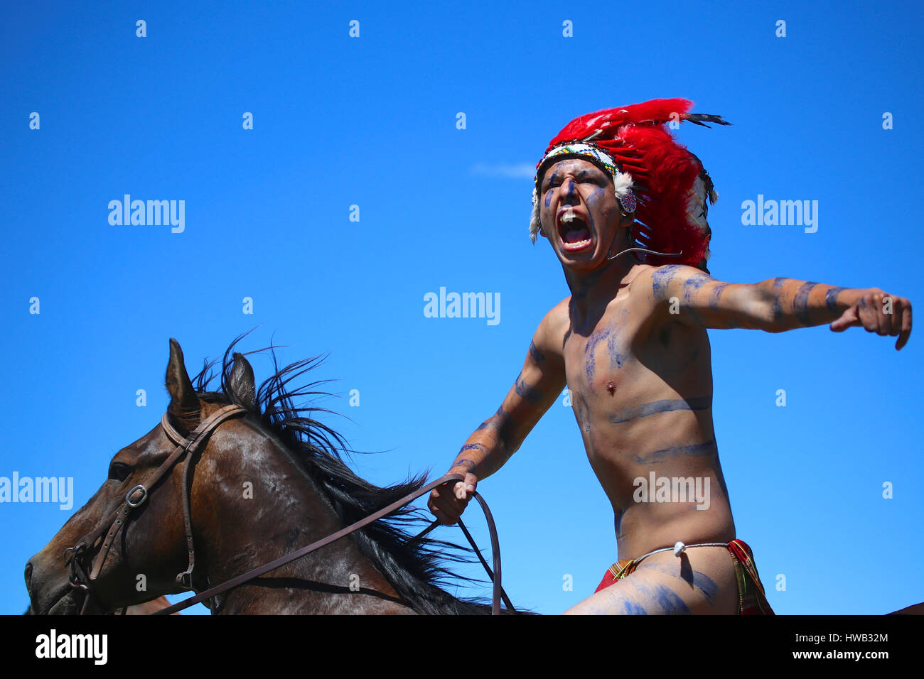 Native American Indian indossando blu vernice di guerra e indossando red feather cerimoniale abito di testa Crazy Horse reenactor nella battaglia di Little Bighorn Montana Foto Stock