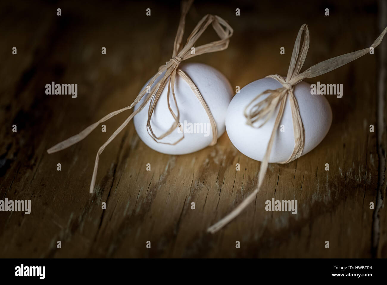 Due bianchi di uova fresche legata con una stringa su un sfondo di legno, fuoco selettivo concetto di pasqua Foto Stock