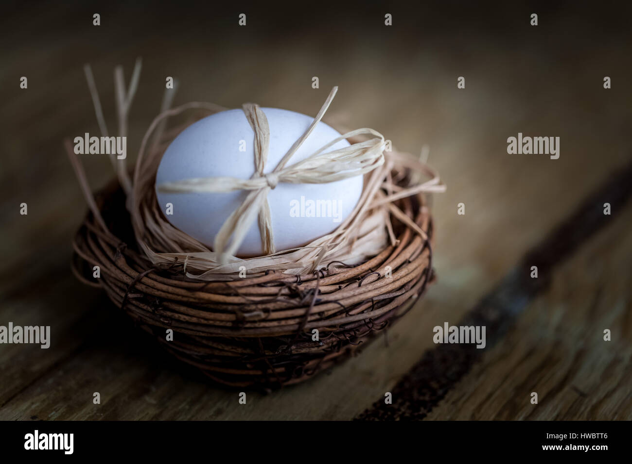 Un uovo nel nido su sfondo di legno, concetto di pasqua Foto Stock