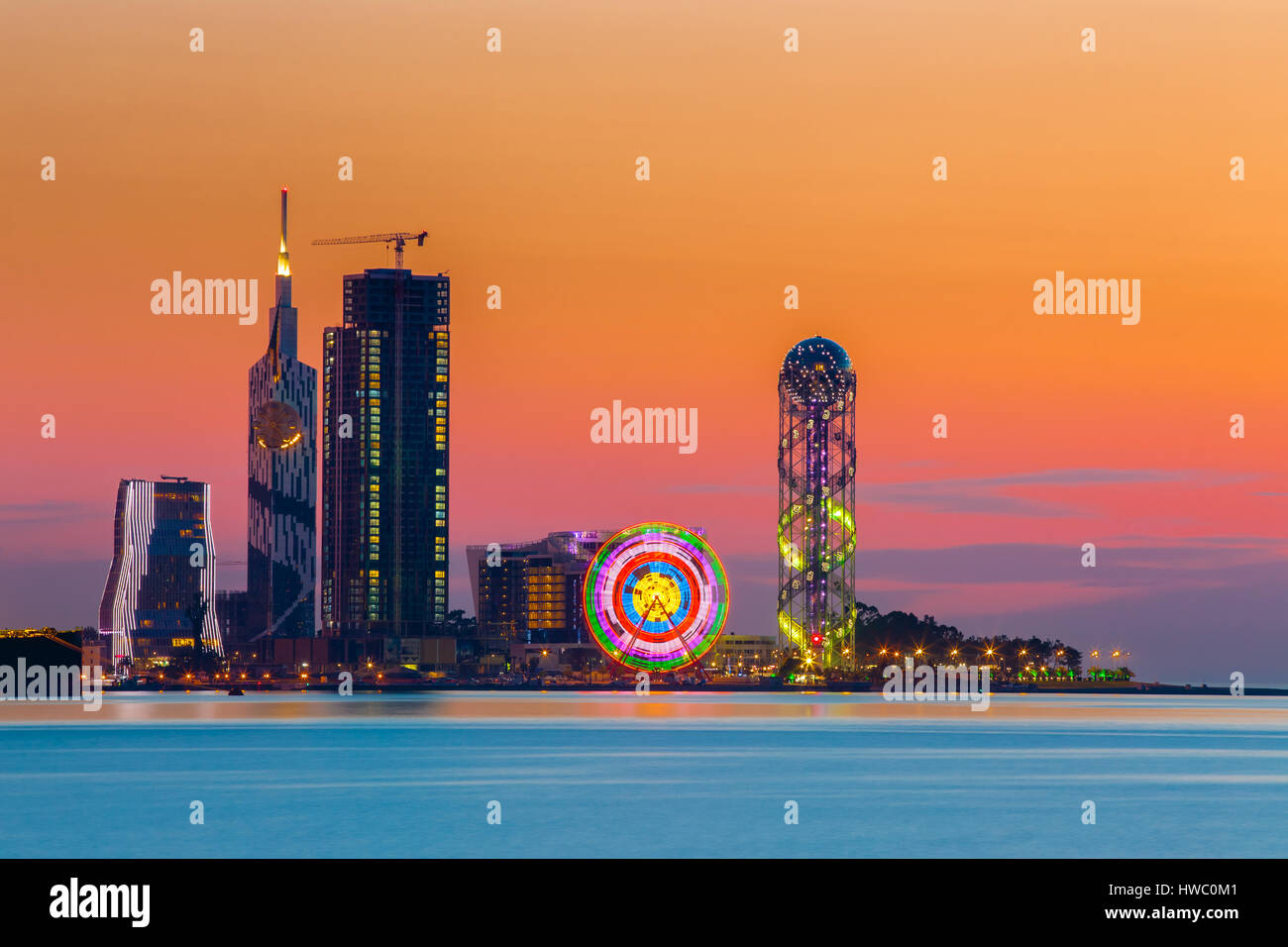 Batumi, Adjara, Georgia. Scena della cittadina al tramonto o l'alba. Luminose del cielo della sera. Vista dal mare spiaggia illuminate con paesaggio urbano moderno Foto Stock