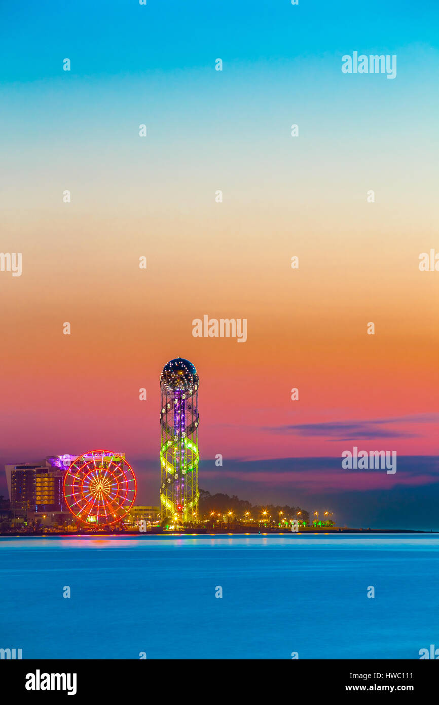 Batumi, Adjara, Georgia. Scena della cittadina al tramonto o l'alba. Luminose del cielo della sera. Vista dal mare spiaggia illuminate con paesaggio urbano moderno Foto Stock