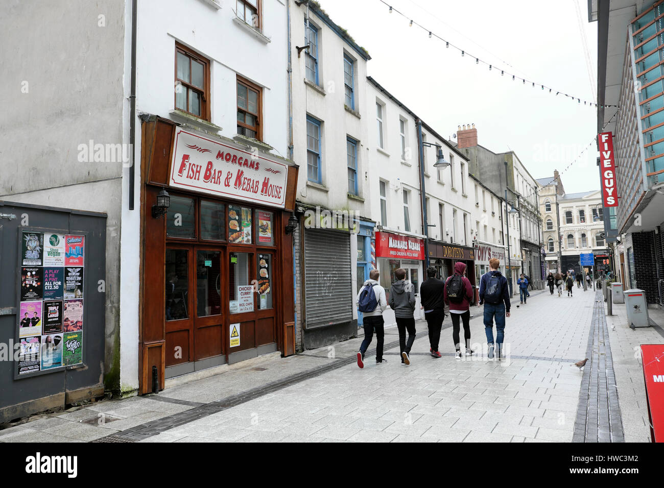 Vista di 5 giovani uomini a piedi passato cinque ragazzi un ristorante fast food sulla Caroline Street nel centro di Cardiff, Galles UK KATHY DEWITT Foto Stock