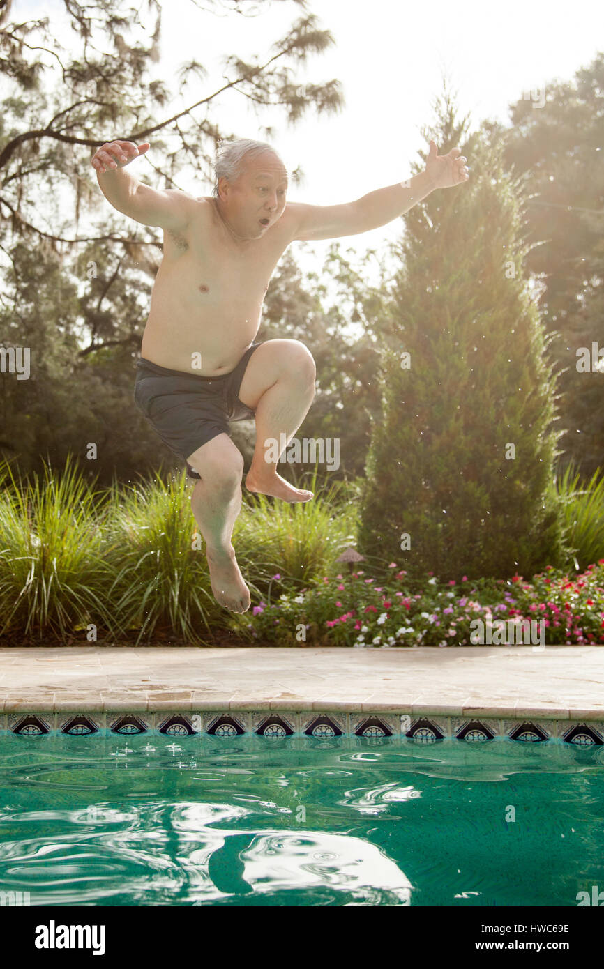 Senior uomo salti in piscina Foto Stock